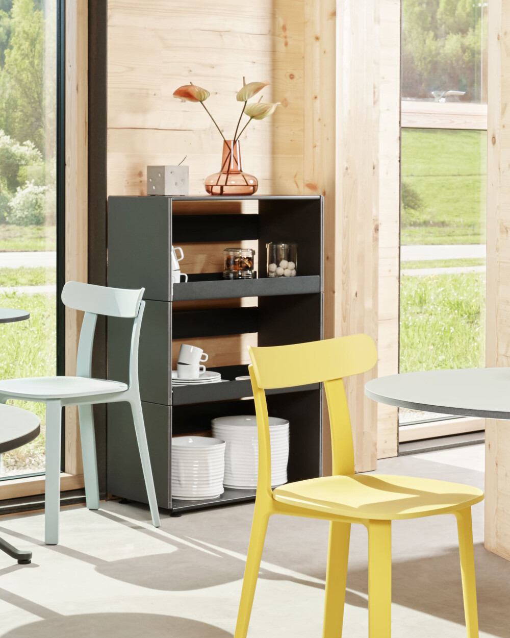 Plus Minus Regal von Faust aus schwarzem Linoleum, bestückt mit Geschirr und Vase, vor einer Holzwand mit großer Fensterfront.