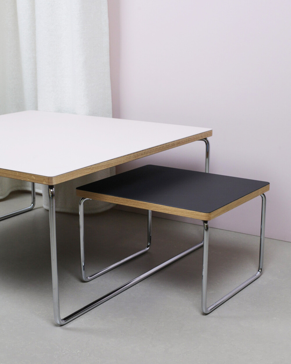 Low & Lower Beistelltische von Faust aus Linoleum in rosa und schwarz mit verchromtem Gestell, vor hellrosa Wand und Vorhang.