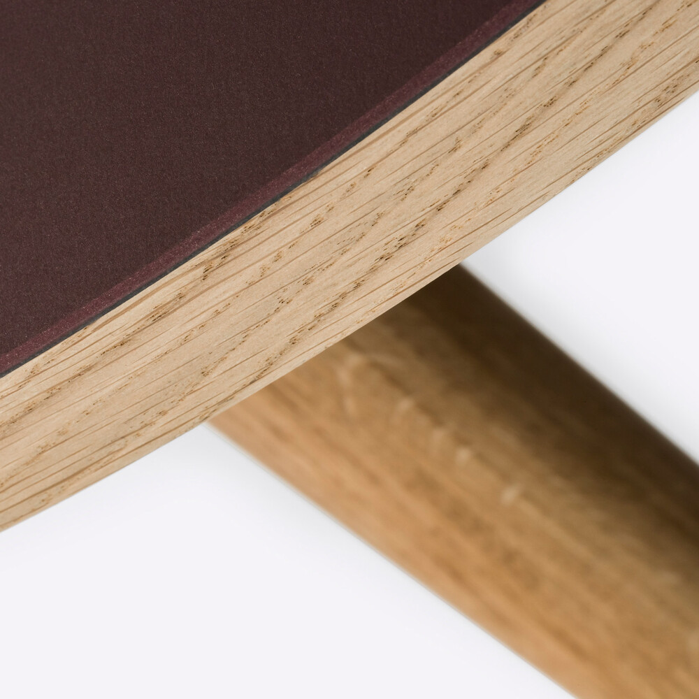 Detail einer runden, mit burgunderfarbenem Linoleum beschichteten Holztischplatte auf MT2-Eichenbeinen von Murken Hansen für FAUST Linoleum