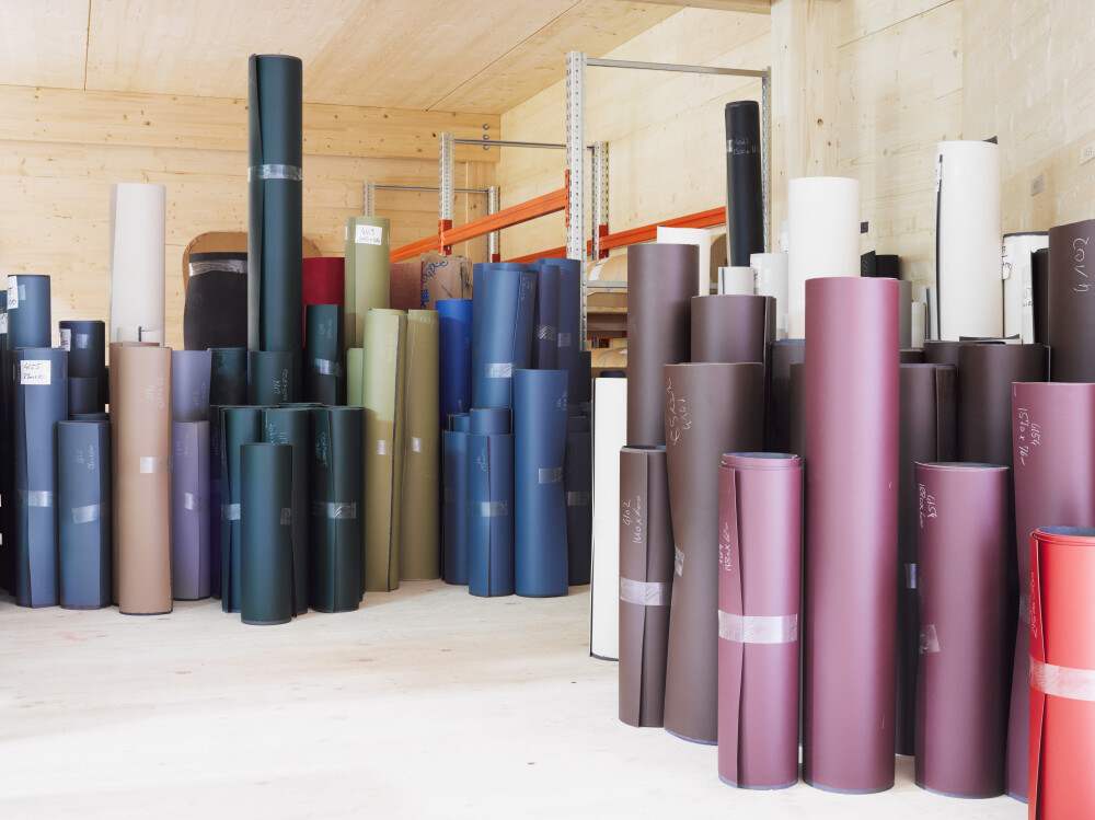 Innenraum der Produktionsstätte von Faust Linoleum in Huglfing, Deutschland, mit einer Gruppe von Linoleumrollen in verschiedenen Farbvarianten