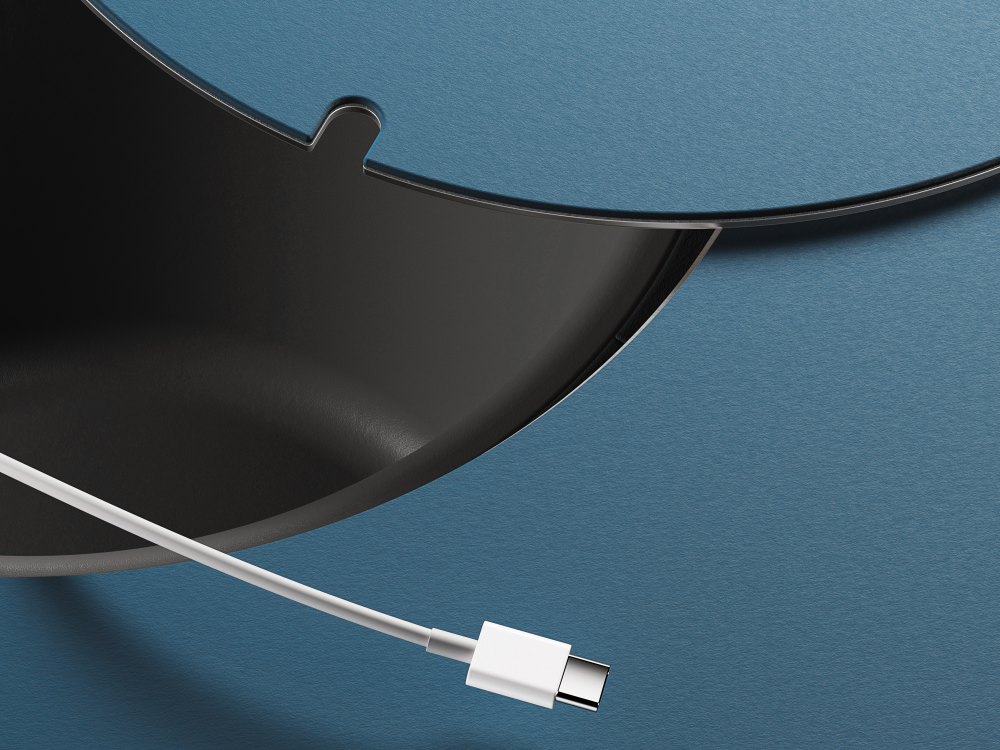 Detailansicht einer runden Kabeldurchführung im ALT Tisch, aus der ein USB-C-Kabel herausgeführt wird.