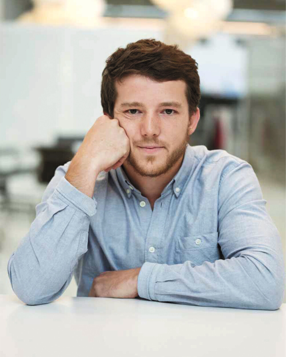 Michel Charlot, Schweizer Industriedesigner – im Porträt für Faust, sitzend am Tisch, mit hellem Hemd und direktem Kamerablick.