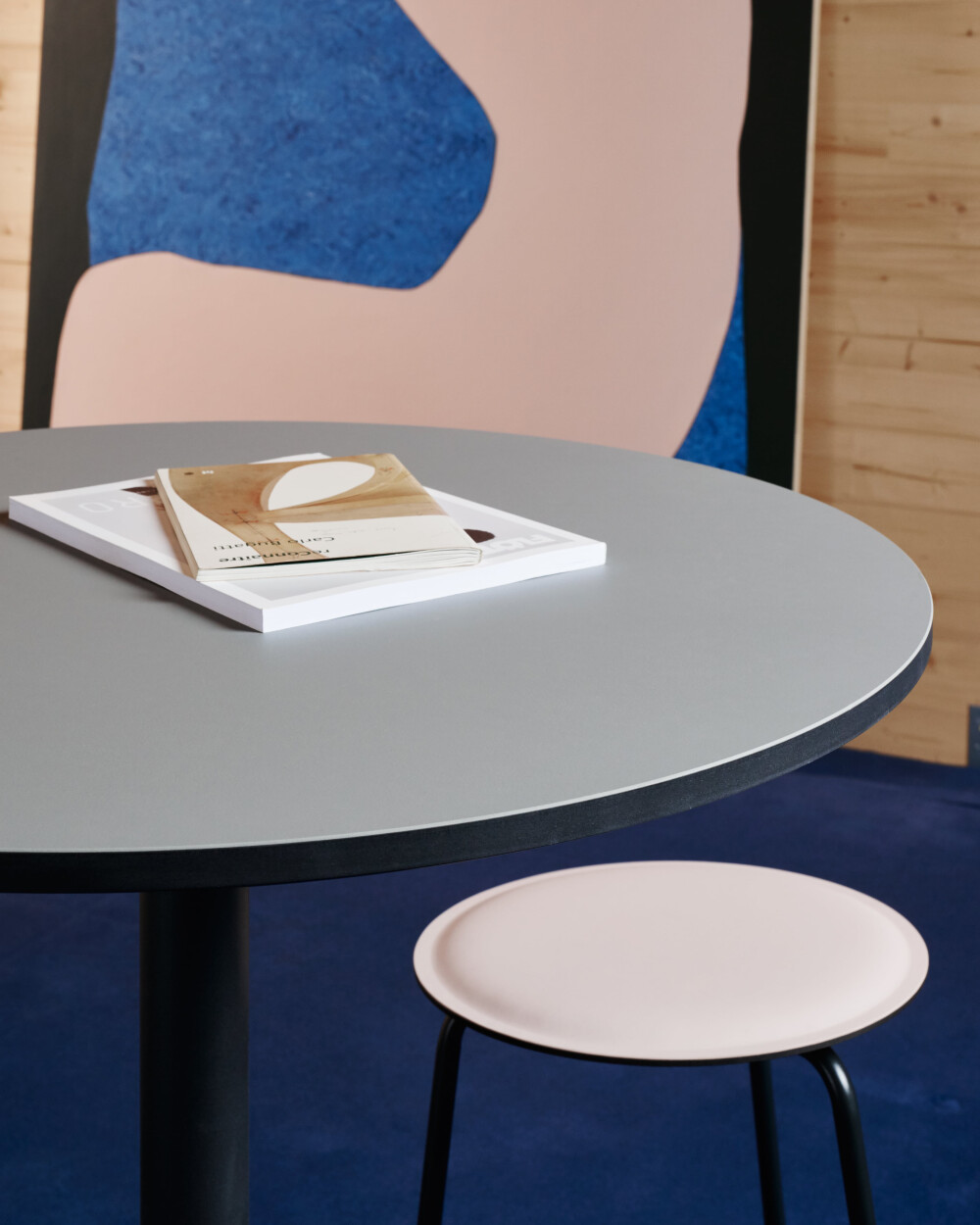 RAVIOLI Hocker mit Linoleum-Sitzfläche in Rosaton an rundem Hochtisch mit grauer Linoleumplatte.