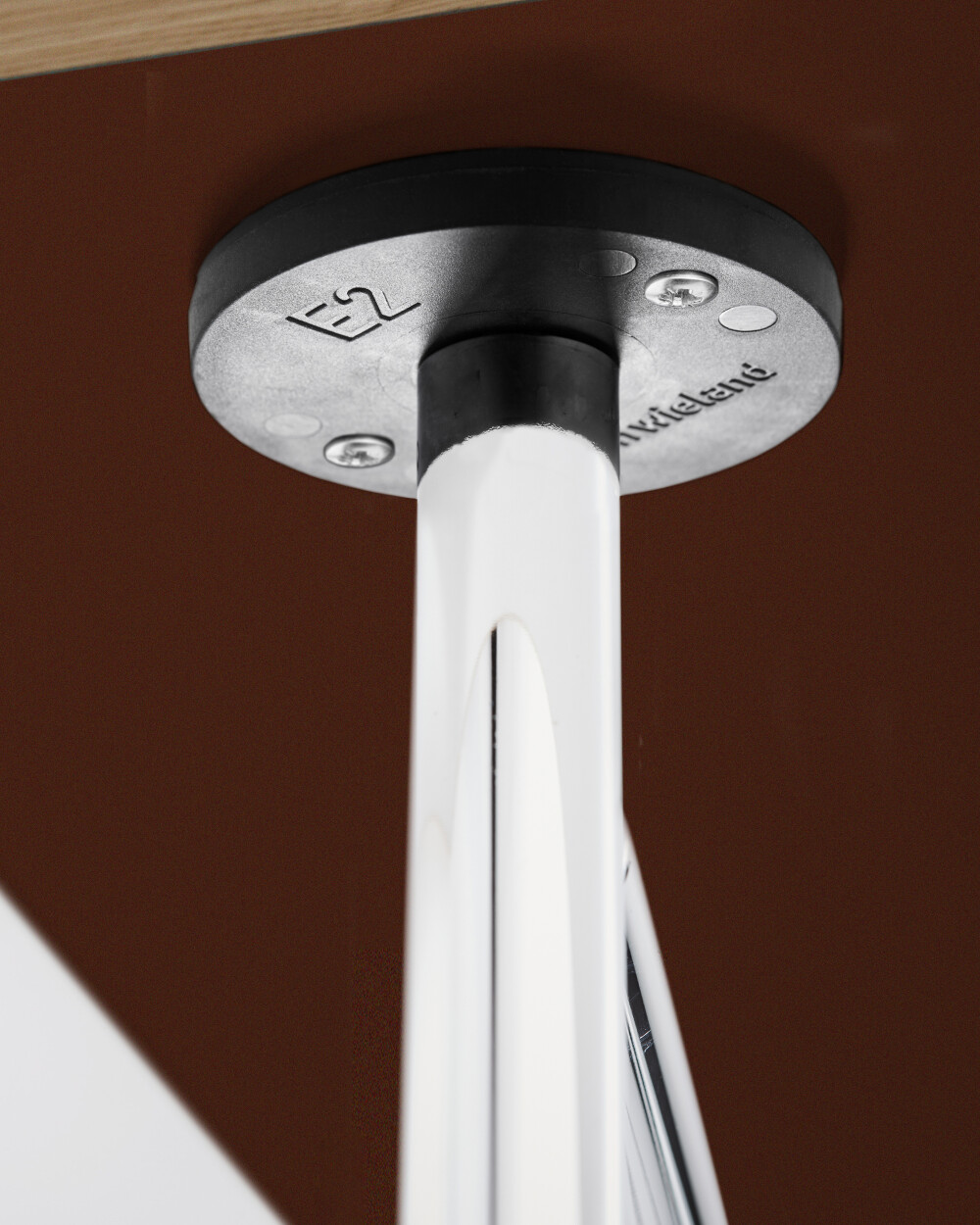 Detailaufnahme eines verschraubten E2 Plattenträgers am Papier beschichteten Tisch, montiert am E2 Metallgestell.